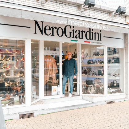 Façade de la boutique ''Marche à Suivre'' à Ans, spécialisée en chaussures et accessoires, avec Jean Milazzo debout devant l'entrée.