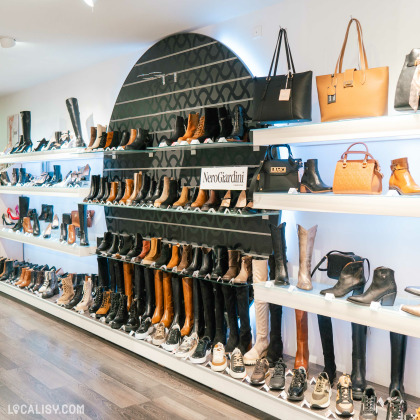 Intérieur de la boutique ''Marche à suivre''à Ans, présentant une large gamme de chaussures et sacs élégants exposés sur des étagères illuminées.