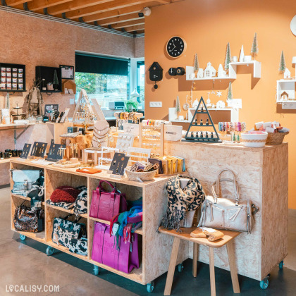 Un présentoir dans le magasin de Shopping et vente au détail Comme une Evidence à Mons-lez-Liège, rempli de bijoux, accessoires de mode, sacs et objets de décoration. L'agencement chaleureux et soigné crée une ambiance accueillante.