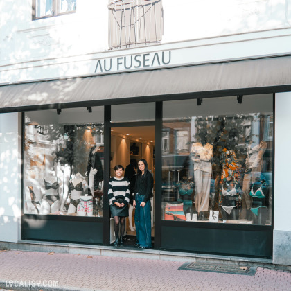 Devanture du magasin de lingerie Au Fuseau Lingerie à Spa avec une vitrine exposant des mannequins portant de la lingerie et des vêtements. Deux personnes se tiennent à l'entrée du magasin.