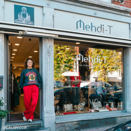 Devanture du magasin de vêtements Mehdi-T à Spa, avec une personne debout à l'entrée. La vitrine expose des sacs à main et des accessoires.