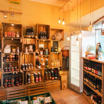 L'intérieur de l'Épicerie La petite Gatte à Aywaille, avec des étagères en bois remplies de produits artisanaux et locaux, comme des confitures, des bouteilles de vin, des sauces, et des conserves.