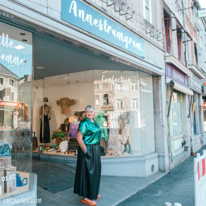 Devanture du magasin de vêtements Annestramgram à Aywaille, une personne se tient debout devant la vitrine. La vitrine du magasin expose divers articles de mode, y compris des sacs à main, des vêtements et des accessoires. Le magasin est situé dans une rue commerçante avec d'autres boutiques visibles en arrière-plan.