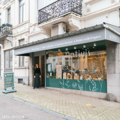 Devanture du magasin de cosmétiques Nativis à Verviers. La façade est décorée avec des illustrations de plantes et des produits de beauté sont visibles à travers la vitrine. L'enseigne indique que le magasin propose des cosmétiques naturels et bio, du maquillage, des idées cadeaux, des ateliers beauté et des soins esthétiques. Une personne se tient à l'entrée du magasin.