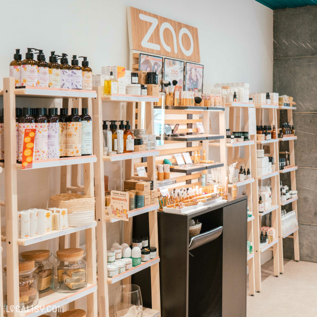 L'intérieur du magasin de cosmétiques Nativis à Verviers, avec plusieurs étagères en bois remplies de divers produits de beauté et de soins personnels. Les étagères contiennent des bouteilles de lotions, des crèmes, des huiles, des pinceaux de maquillage, et d'autres articles de soins.