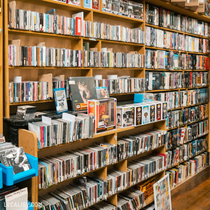 L'intérieur du magasin de jeux vidéo All4Addicts à Verviers, avec des étagères remplies de CD, de DVD et de figurines de collection. Il y a une grande variété de produits culturels, y compris des albums de musique, des films et des objets de collection.