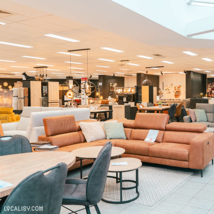 L'intérieur du magasin de meubles Vrijens à Juprelle, avec divers articles de mobilier exposés. On y voit des canapés, des tables, des chaises et des luminaires modernes. Le magasin semble spacieux et bien organisé, avec des meubles disposés de manière à permettre aux clients de circuler facilement.