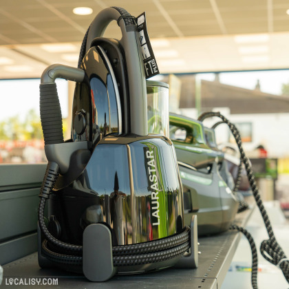 Un appareil électroménager de la marque Laurastar, probablement un fer à repasser ou un système de repassage, exposé dans le magasin d'électroménager Schoofs Electro à Sprimont. L'appareil est noir avec des accents gris et est posé sur une étagère.