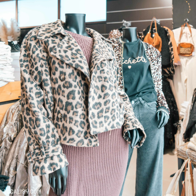 Deux mannequins dans le magasin de vêtements pour femmes DC Fashion Store Baugnez à Malmedy. Le mannequin de gauche porte un manteau à motif léopard par-dessus une robe en tricot côtelé de couleur mauve. Le mannequin de droite porte un t-shirt noir avec l'inscription "cheta" et un cœur, ainsi qu'un pantalon en jean gris et une veste à paillettes.