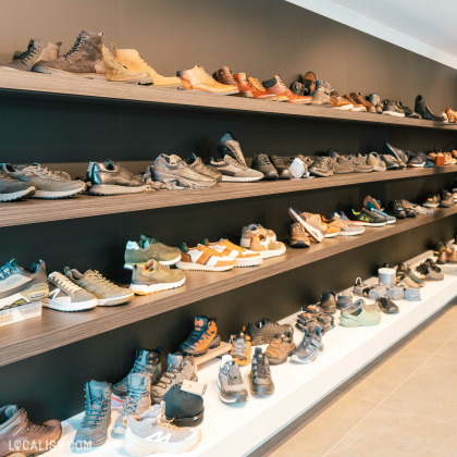 Des étagères remplies de chaussures dans le magasin de chaussures Maison Brüls à Malmedy. Les étagères contiennent une variété de chaussures, y compris des bottes, des baskets et des chaussures de randonnée, disposées de manière ordonnée.