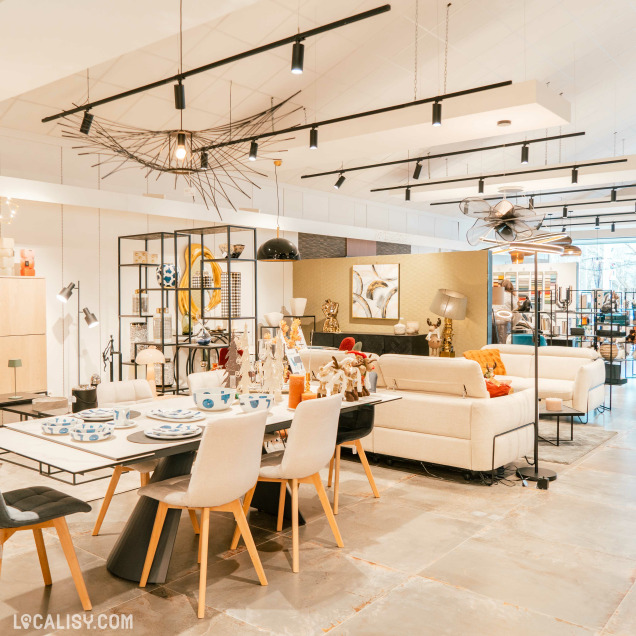 Une variété de meubles modernes, y compris des canapés, des chaises, des tables, et des étagères à l'intérieur du magasin de luminaires Espace Design à Sprimont. Il y a également plusieurs luminaires suspendus au plafond, ainsi que des objets décoratifs sur les tables et les étagères. L'agencement est lumineux et bien organisé, mettant en valeur les différents articles en vente.