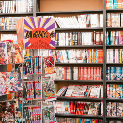 Des étagères remplies de volumes de mangas variés dans la librairie de bandes dessinées Kazabulles à Liège. Un présentoir rotatif au premier plan affiche également plusieurs mangas. Le panneau au-dessus du présentoir indique "MANGA" avec un design coloré. Les étagères en arrière-plan sont bien organisées et contiennent une grande variété de titres, ce qui rend cette section attrayante pour les amateurs de mangas.