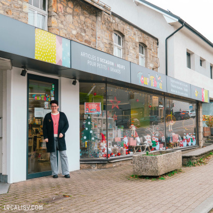 Devanture magasin de produits d'occasion Toup'tibou à Waimes. Le magasin propose des articles d'occasion et neufs pour petits et grands. La vitrine est décorée avec des décorations de Noël, y compris des figurines de Père Noël, des étoiles et des arbres de Noël. Une personne se tient devant l'entrée du magasin. L'enseigne du magasin est visible au-dessus de la vitrine, avec des couleurs vives et le nom "Toup'tibou".