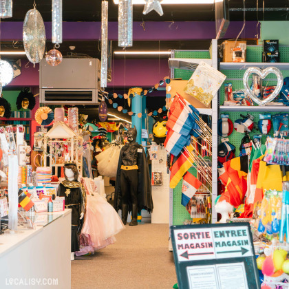 Intérieur du magasin Funny Party à Rocourt avec costumes, drapeaux et accessoires pour événements festifs.