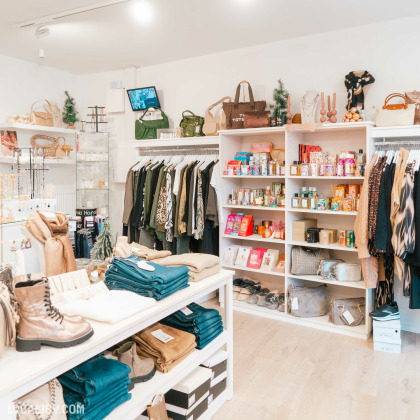 Intérieur de la boutique D'après Elles Fashion Store à Comblain-au-Pont avec des chaussures, des bougies et d'autres accessoires mode