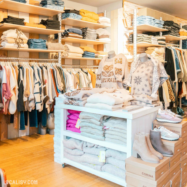 Intérieur du magasin Ma-au à Spa avec vêtements pour femme soigneusement rangés.