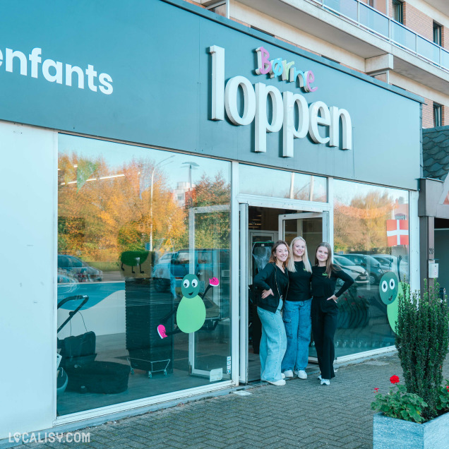 Devanture du magasin Børneloppen Liège – Façade accueillante avec une grande enseigne colorée et des vitrines décorées. Trois membres de l’équipe souriantes posent devant l’entrée vitrée du magasin.