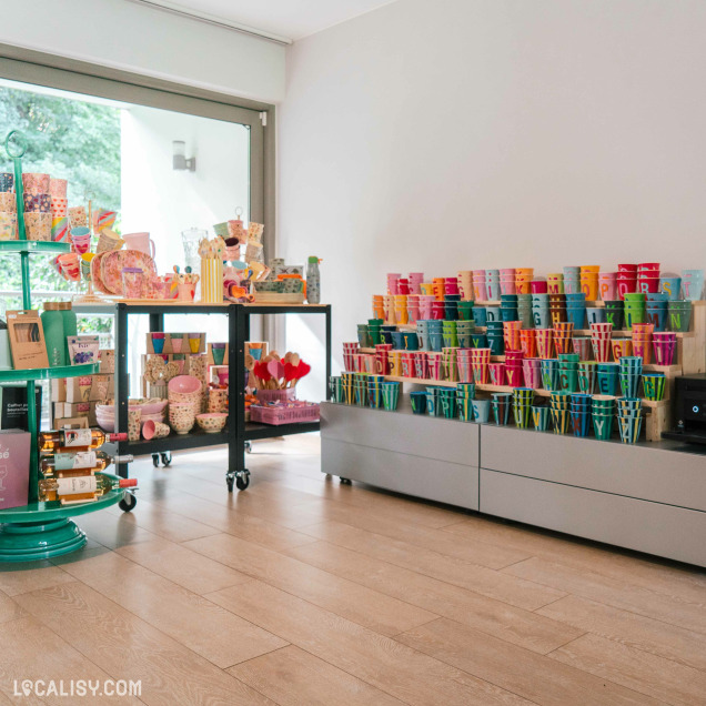 Vue d’ensemble de L’Appart Concept Store à Embourg, mettant en avant des étagères remplies de tasses, assiettes et articles colorés pour la maison.