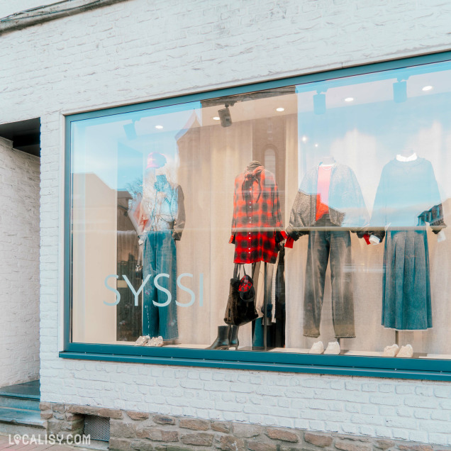 Vitrine du magasin Syssi à Battice – Présentation soignée de mannequins habillés avec des tenues tendances et élégantes. Le logo Syssi est affiché sur la vitre.