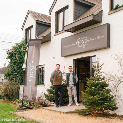 Magasin de vins et spiritueux Les Vignes en Ville à Beaufays – façade extérieure avec deux gérants devant l'entrée décorée pour Noël.