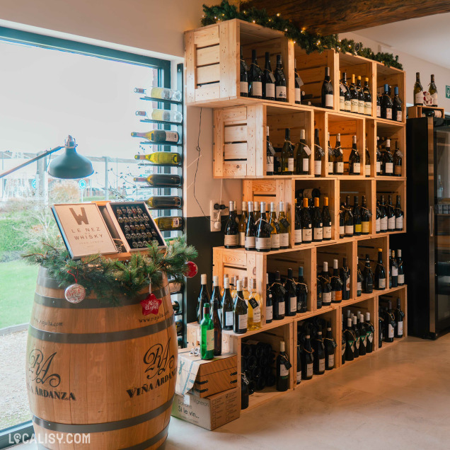 Magasin de vins et spiritueux Les Vignes en Ville à Beaufays – coin décoré avec fût en bois et présentoirs de bouteilles