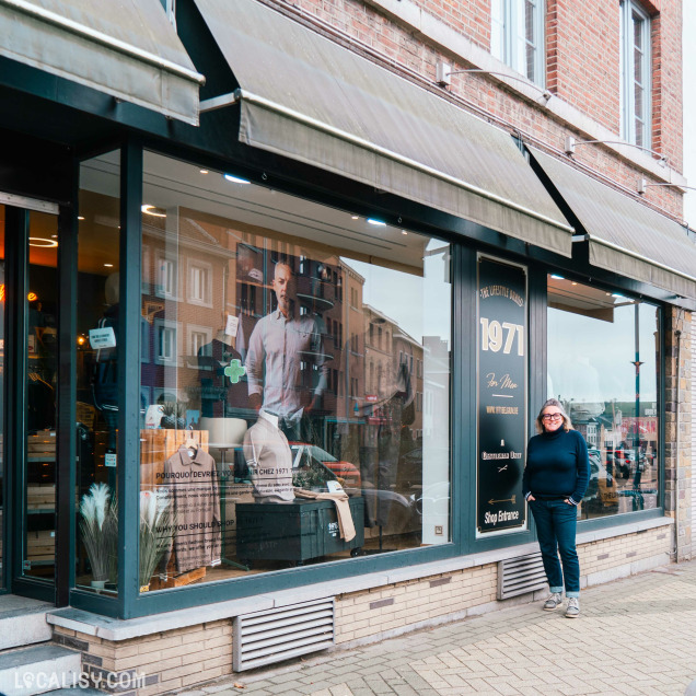 Façade d'une boutique de mode masculine nommée "1971 For Men" avec une vitrine mettant en avant des vêtements et accessoires modernes. Une femme souriante se tient devant l'entrée.