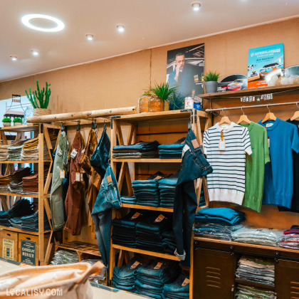 Espace de la boutique dédié aux jeans et pulls, avec des étagères en bois contenant des vêtements bien organisés et des plantes décoratives pour une ambiance accueillante.