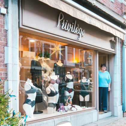 La devanture du magasin "Boutique Privilège" à Visé, avec des mannequins présentant des ensembles de lingerie dans la vitrine. Une femme se tient à l’entrée.