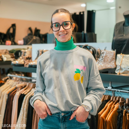 Une vendeuse souriante au magasin de vêtements By Lou H à Neupré.