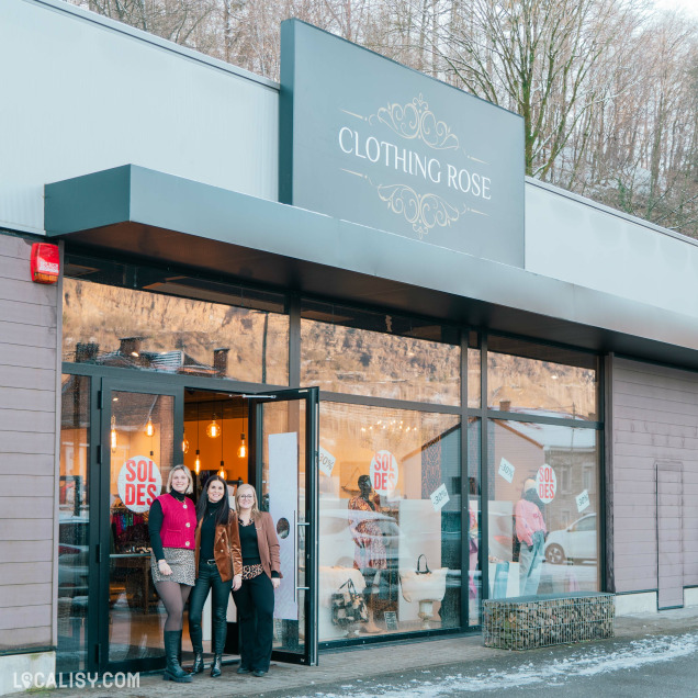 Façade extérieure du magasin Clothing Rose à Aywaille avec trois personnes souriantes devant l’entrée.