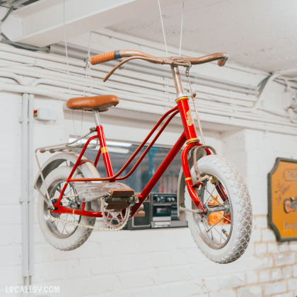 Vélo vintage rouge suspendu dans l'atelier de Velo Vrac Custom à Grivegnée.