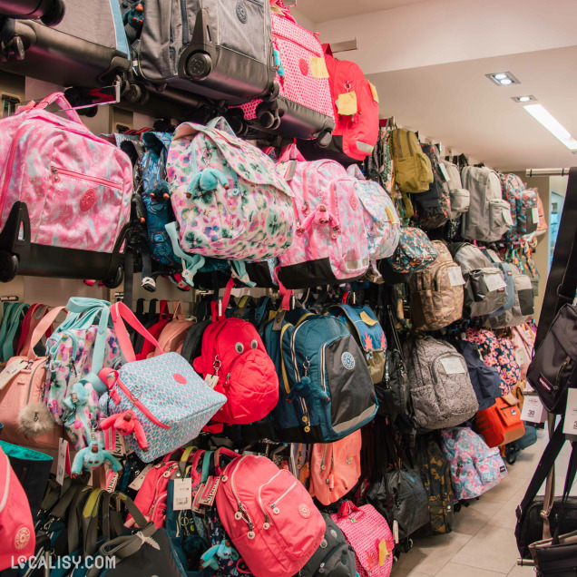 Rayons de sacs à dos colorés pour enfants et adolescents, suspendus et empilés, avec des motifs variés et des modèles de différentes tailles.