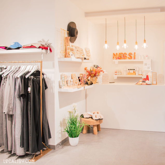 Comptoir de la boutique Nessi Collection avec des bijoux et accessoires soigneusement exposés. L’ambiance chaleureuse est renforcée par un éclairage suspendu et une décoration minimaliste.