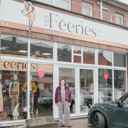 Façade du magasin Les Fééries by Val-Lou, boutique de seconde main de marques pour femmes et enfants. Une femme souriante se tient devant l’entrée vitrée, avec des mannequins en vitrine et un logo féérique en haut du magasin.