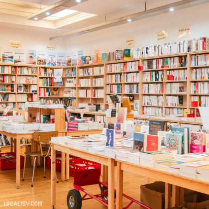 Intérieur de la librairie "La Traversée" avec des étagères en bois remplies de livres classés par thématique, comme littérature, essais et récits de voyage. Des tables en bois affichent les nouveautés et les recommandations.