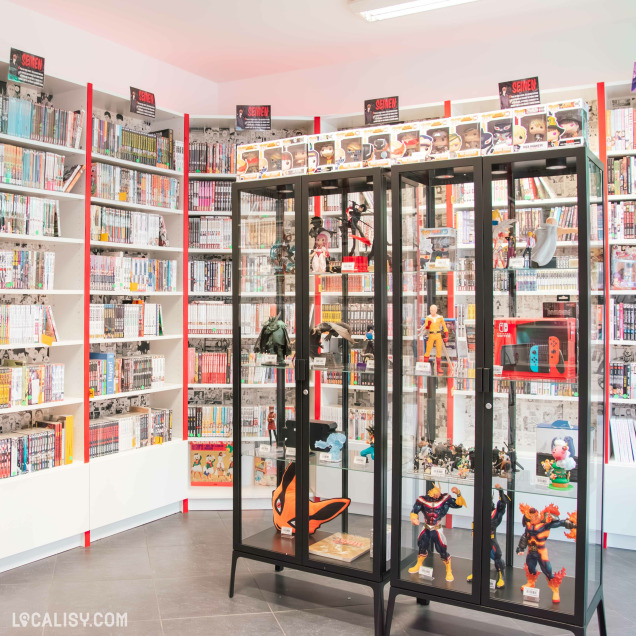 Vue intérieure du magasin Manga Cash avec des vitrines remplies de figurines issues de mangas et d’animes populaires. Derrière, des étagères bien garnies de mangas classés par catégorie.